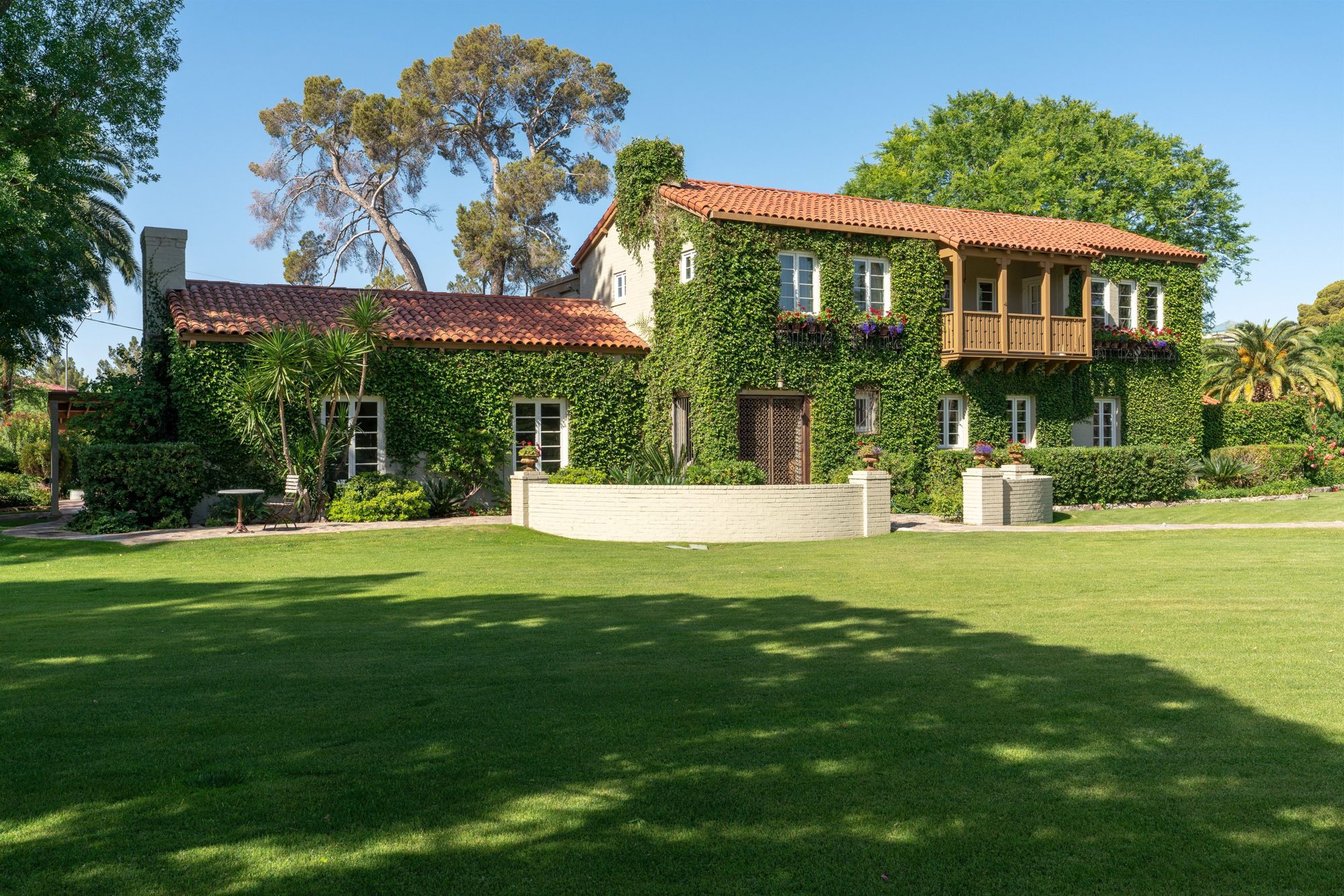 Ivy-covered historic estate with a tile roof, balcony and broad lawn in central Phoenix